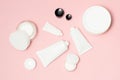 White cosmetic tubes and cream containers on pink background