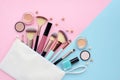 A white cosmetics bag with makeup products spilling out on to a color background. Royalty Free Stock Photo