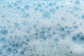 White cosmetics foam texture on blue background. Cleanser, shampoo bubbles, wash - liquid soap, shower gel, shampoo Royalty Free Stock Photo