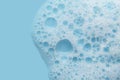 White cosmetics foam texture on blue background. Cleanser, shampoo bubbles, wash - liquid soap, shower gel, shampoo Royalty Free Stock Photo