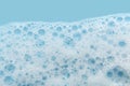 White cosmetics foam texture on blue background. Cleanser, shampoo bubbles, wash - liquid soap, shower gel, shampoo Royalty Free Stock Photo