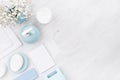 White cosmetics products set, mock up for body and skin care, blue ceramic bowl, silver accessories, flowers on white wood board.