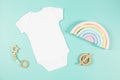 White cotton baby short sleeve bodysuit and natural wooden toy on light green background. Infant onesie mockup. Blank