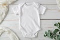 White cotton baby short sleeve bodysuit on white wooden background. Infant onesie mockup. Blank gender neutral newborn Royalty Free Stock Photo