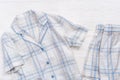 White cotton pajamas with blue checks or stripes, on a white wooden background.  Nightwear for sleeping. Top view Royalty Free Stock Photo