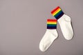 White cotton socks with rainbow stripes on gray background, top view, copy space