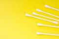 White cotton swabs or buds are on yellow uniform background view from above with clear area of half of photo for labels or headers