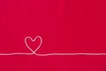 White cotton thread in heart shape on red fabric background Royalty Free Stock Photo