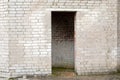 White cracked brick wall with a doorway