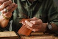 White craftsman sewing while making leather wallet