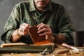 White craftsman sewing while making leather wallet
