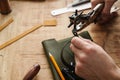 White craftsman using tool while working with leather