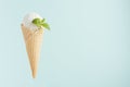 White creamy ice cream in crisp waffle cone with green mint leaf on soft light pastel green background, copy space. Royalty Free Stock Photo