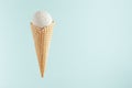 White creamy ice cream in crisp waffle cone on soft light pastel green background, mock up, copy space.