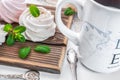 White creamy marshmallow handmade. Adorned with mint leaves. Tea in a white cup with a blue ornament. On a wooden background. Royalty Free Stock Photo