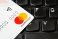 White credit or debit card Mastercard for cashless payments with pay pass on a black laptop keyboard