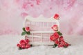 A white crib for a newborn baby adorned with pink rosebuds stands on a floral pink background Royalty Free Stock Photo
