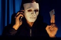 White criminal mask calling to credit card owner to threaten ransom. Pecuniary.