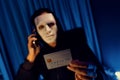 White criminal mask calling to credit card owner to threaten ransom. Pecuniary.