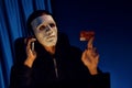 White criminal mask calling to credit card owner to threaten ransom. Pecuniary.