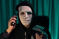 White criminal mask calling to credit card owner to threaten ransom. Pecuniary.