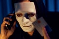 White criminal mask calling to credit card owner to threaten ransom. Pecuniary.