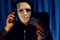 White criminal mask calling to credit card owner to threaten ransom. Pecuniary.