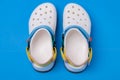 White Croc slippers with straps on a blue background. Comfortable unisex beach shoes Royalty Free Stock Photo