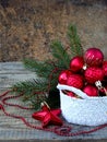 White Crochet round basket with red Christmas decorations on wooden background. New Year and Xmas card background. Copy space. Sel Royalty Free Stock Photo