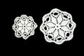 White crocheted coaster lace doily on black background.