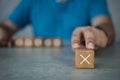 White cross mark, x, Wrong mark sign, Man showing a rejection sign in wooden cube