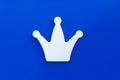 .White crown on a blue background. Decor element, a symbol of power, wealth. Headdress of monarch. The king of chess..