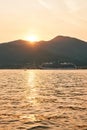 White cruise ship sails on the sea against the backdrop of mountains at sunset Royalty Free Stock Photo