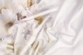White crumpled wrinkled fabric with waves and large white flowers, daisies, background crumpled tissue