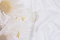 White crumpled wrinkled fabric with waves and large white flowers, daisies, background crumpled tissue