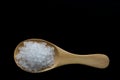 White crystals sea salt on wooden spoon on black background