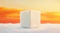A white cube sits on a snowy surface against a sunset sky. Royalty Free Stock Photo