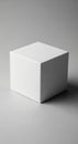 White cube on a smooth gray surface, made of cardboard or similar material. The lighting casts a Royalty Free Stock Photo