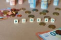 Cubes spelling Dinero in front of Spanish dinero bills and coins on the table Royalty Free Stock Photo