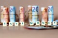 Cubes spelling Save Money on the table with Spanish Dinero bills and coins