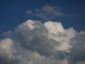 White cumulus in the blue sky partially obscured by the gray nimbostratus
