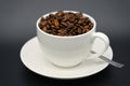 A white cup with aromatic coffee beans with a spoon on black background Royalty Free Stock Photo