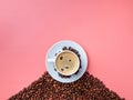 White cup with aromatic coffee on a hill of coffee beans on a pink background Royalty Free Stock Photo