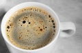 White cup of black coffee from above. top view of coffee bubble close up