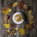 White cup with black coffee in a circle of colored dry leaves on old wooden background. Leaves in a circle with mug of Royalty Free Stock Photo
