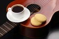 White cup with black coffee and cookies lying on the acoustic gu