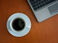 A white cup of black coffee and a laptop on a desk during home office Royalty Free Stock Photo