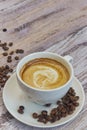 White cup with black coffee with milk. Handful of coffee beans on a wooden table. vertical view of drink with coffee. Copy space