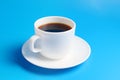 White cup with black coffee on a saucer on