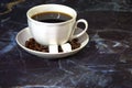 White cup of black coffee on a saucer decorated with coffee beans and sugar cubes Royalty Free Stock Photo